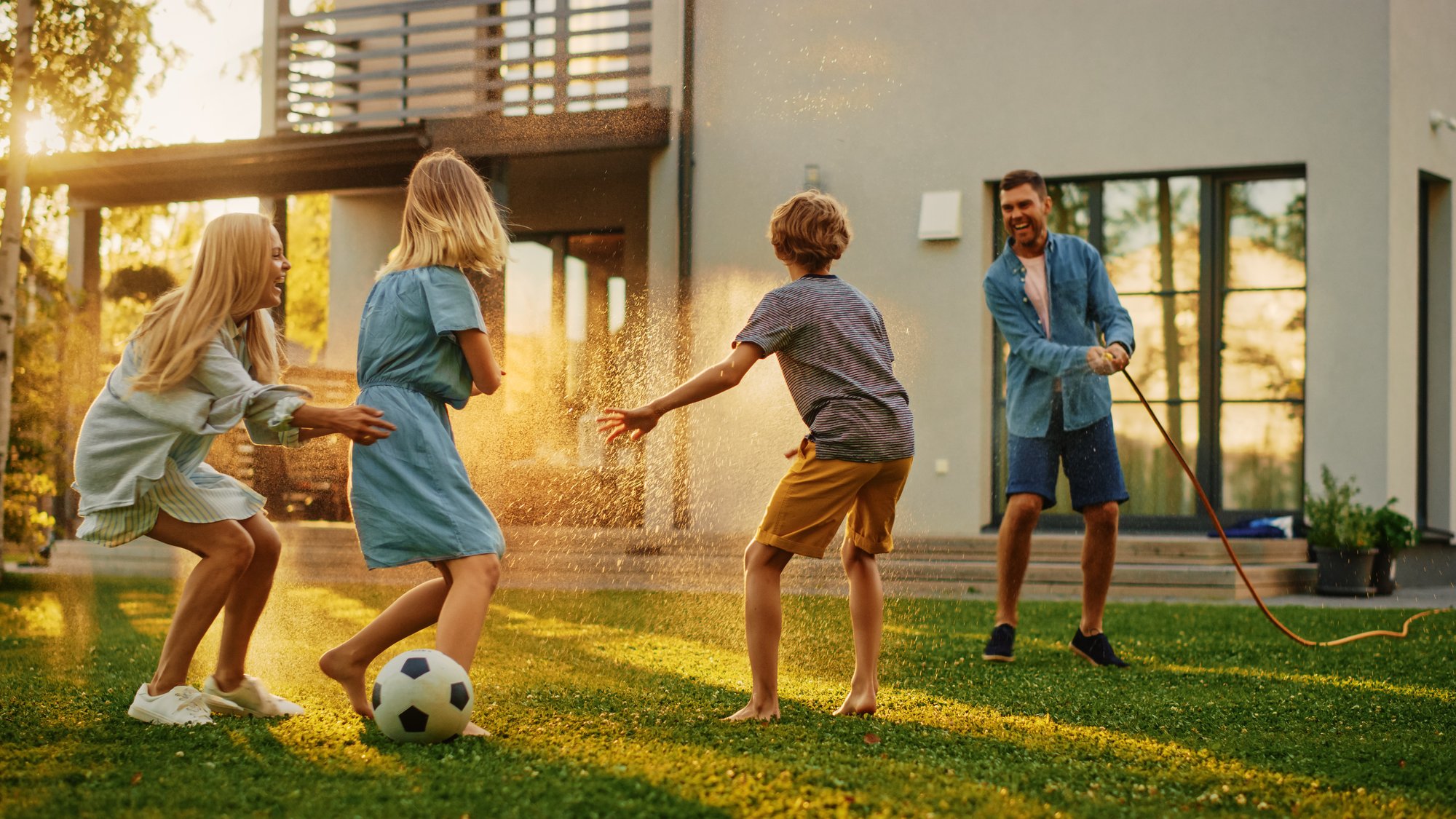 family playing soccer outside of a modern home