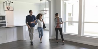 A couple and a real estate agent walk through an empty house. 
