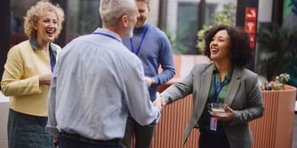 A smiling woman shakes hands with a man in an office. 