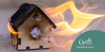 A wooden toy house is engulfed in flames and smoke. 