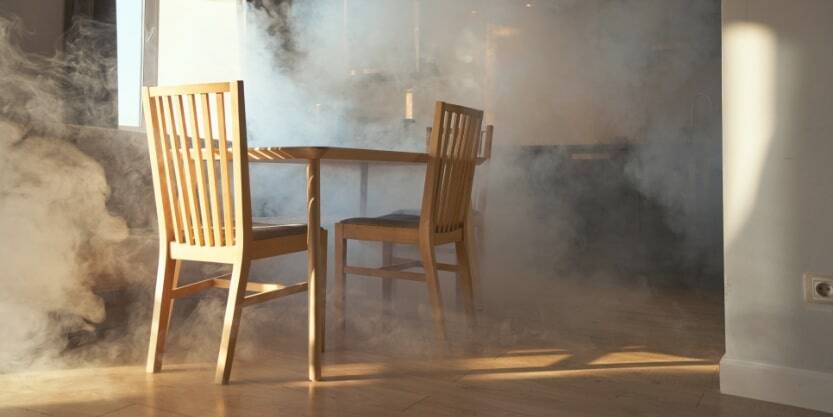 A kitchen table and chairs are in a room filled with smoke.