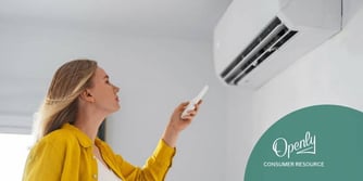 A woman in a yellow sweater controls a mini-split air conditioner with a remote. 