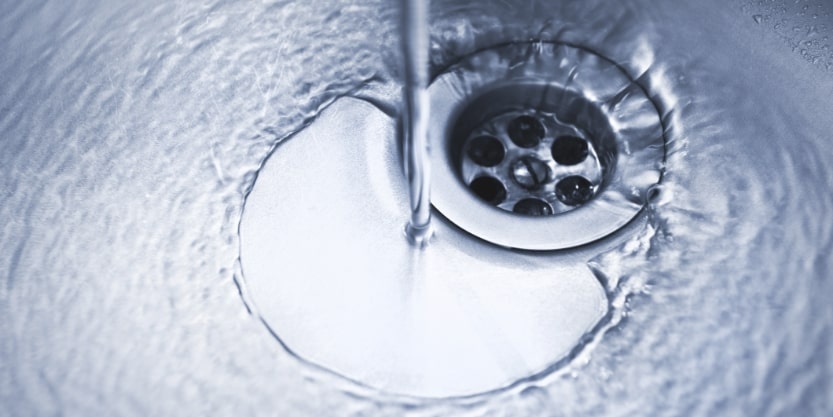 Water runs down a stainless steel sink drain