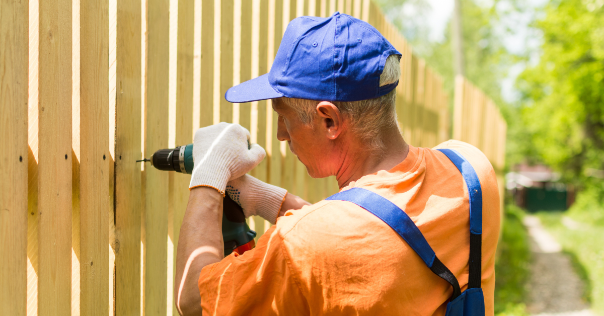 A professional repairman fixes a fence