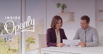 A smiling man and woman look at paperwork together. 