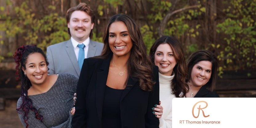 The staff of RT Thomas Insurance smiles at a camera. 