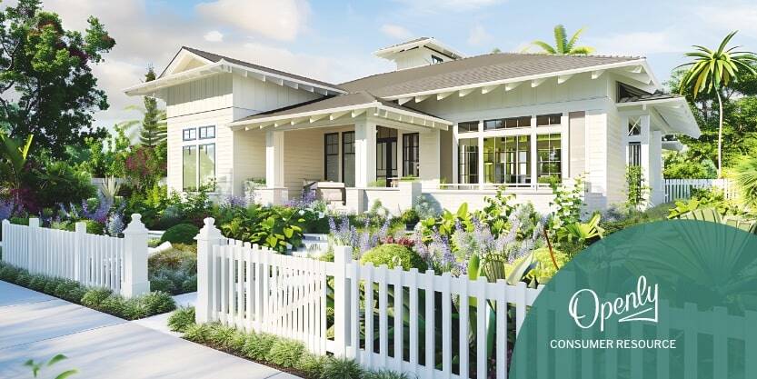 A house with a white picket fence and flower garden. 