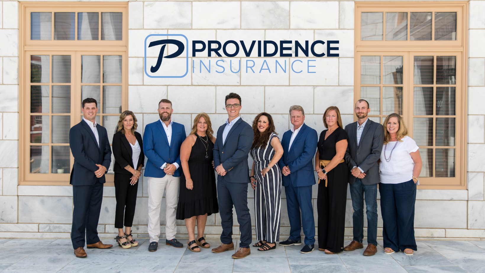 Ten people from Providence Insurance Advisors stand in front of a building. 
